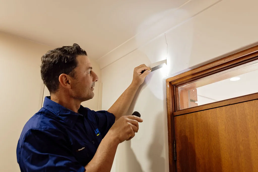 Anthony Capasso using a moisture meter above an internal doorway